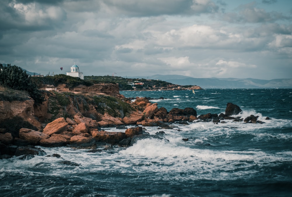 white lighthouse on brown rock formation near body of water during daytime