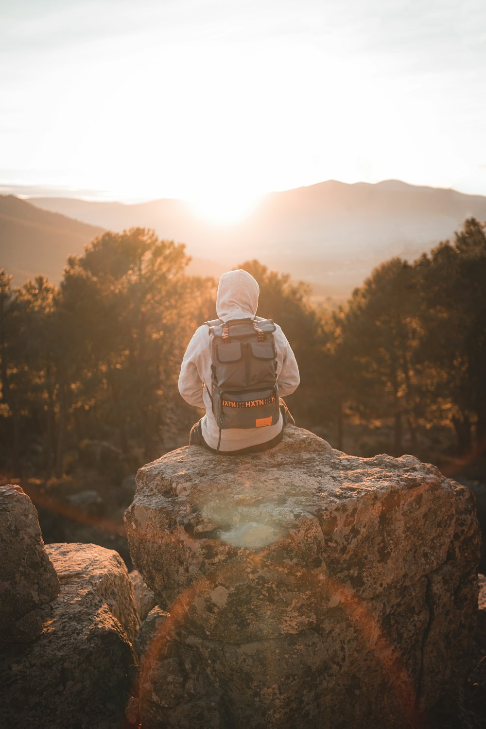 man in gray hoodie sitting on gray rock during daytime