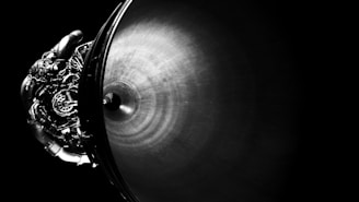A detailed image of a sleek, metallic rocket engine nozzle, with intricate piping and mechanical components. The composition emphasizes the contrast between the shiny, textured metal surface and the dark background.