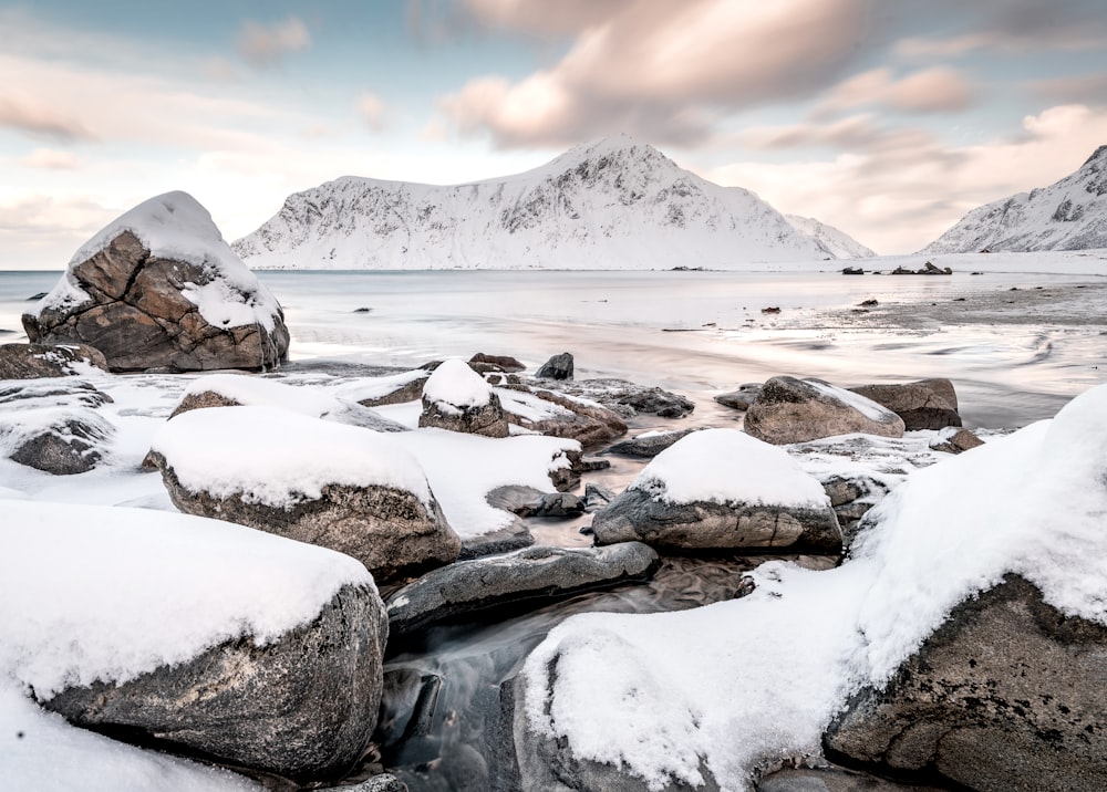 snow covered field near mountain under cloudy sky during daytime