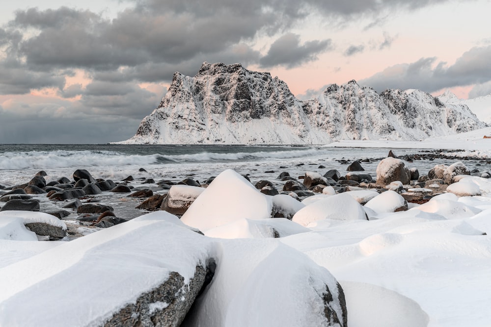 montanha rochosa branca e marrom perto do corpo de água durante o dia