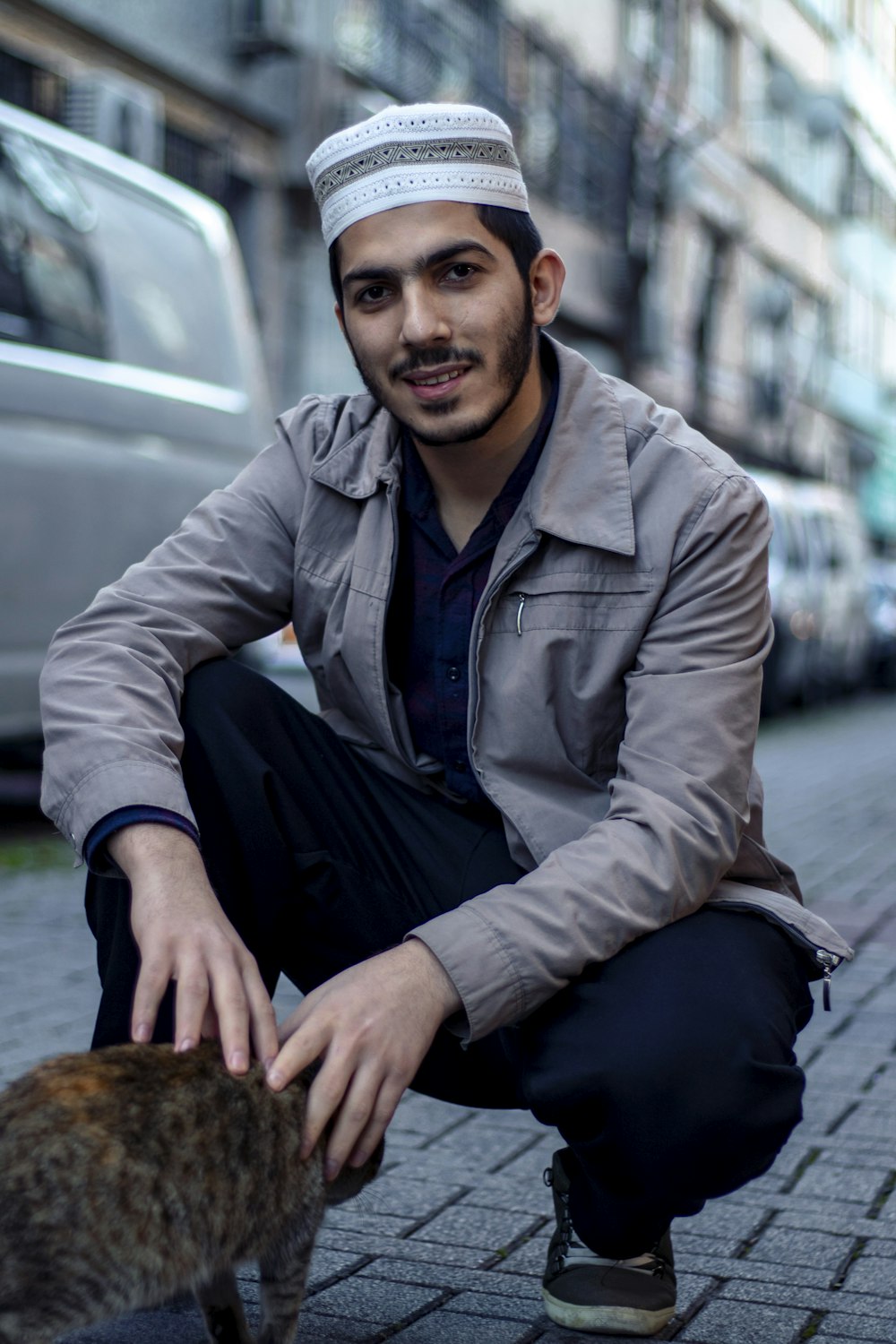 man in gray dress shirt and black pants sitting on gray pavement