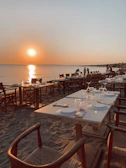 Elegant fine dining setup on a beach with muted gold accents in fading daylight.