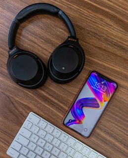 black and purple headphones beside white computer keyboard