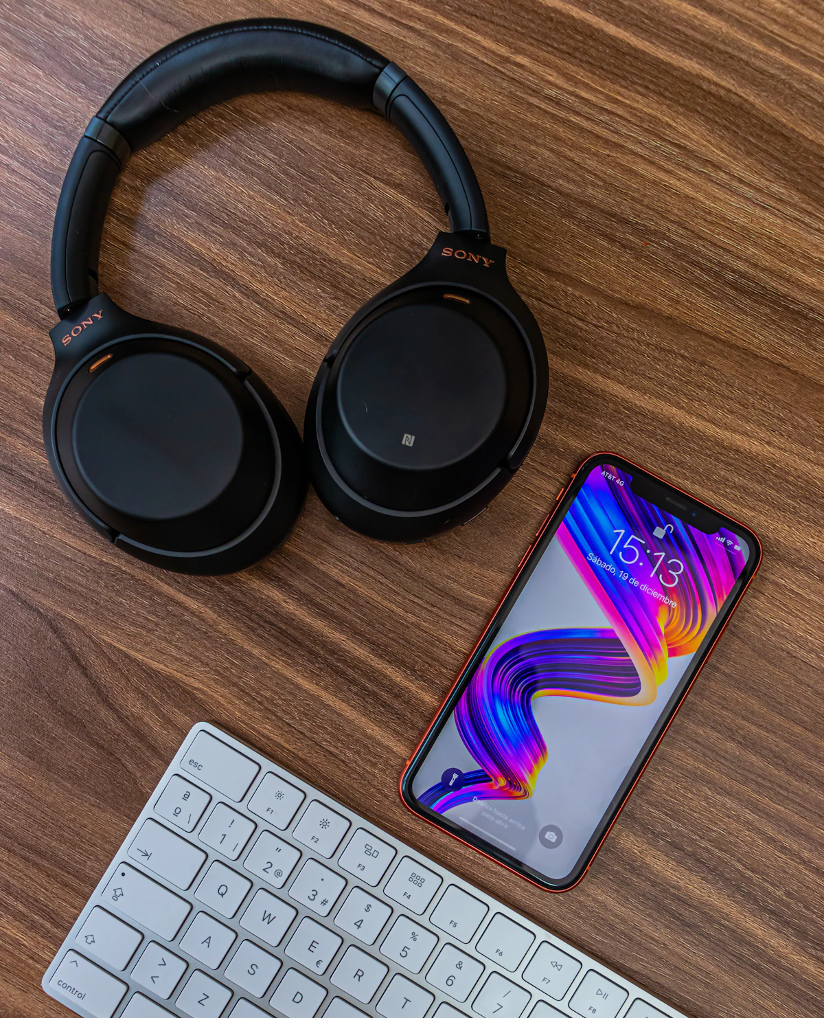 Over-ear headphones beside a keyboard and smartphone