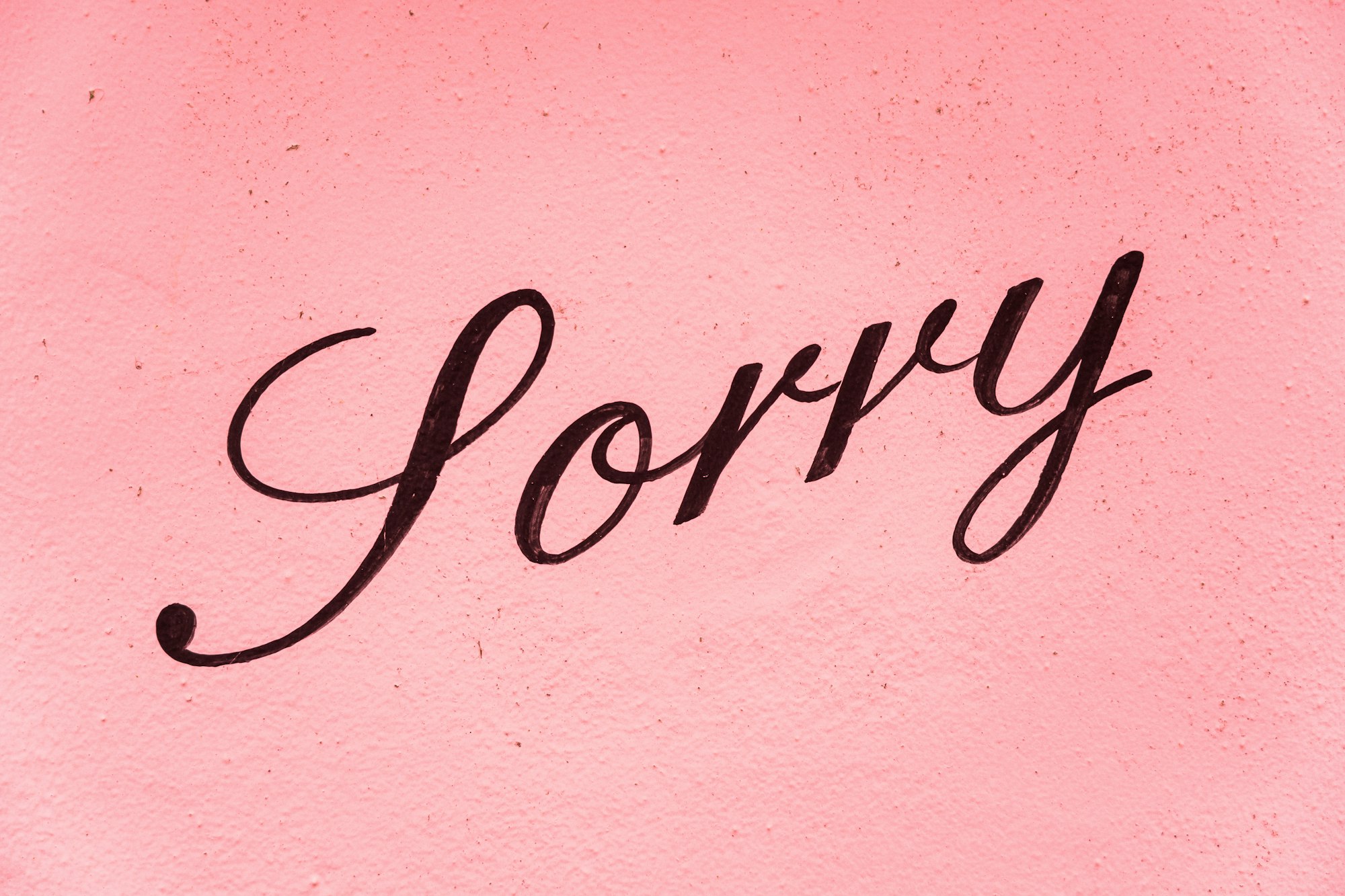 A sign saying sorry on a pink background.