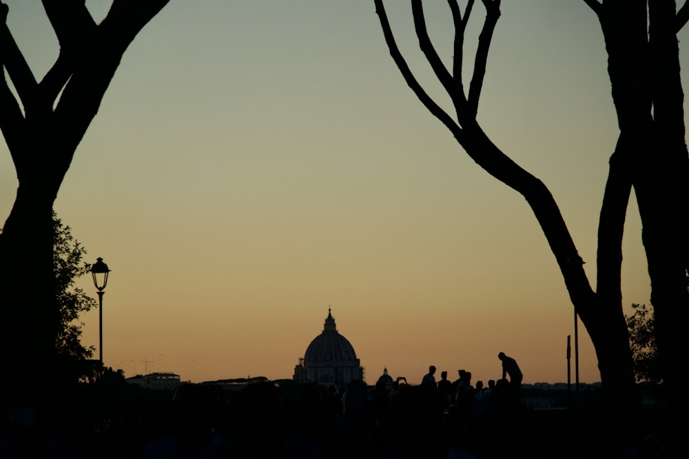 silhouette of people standing near building during sunset