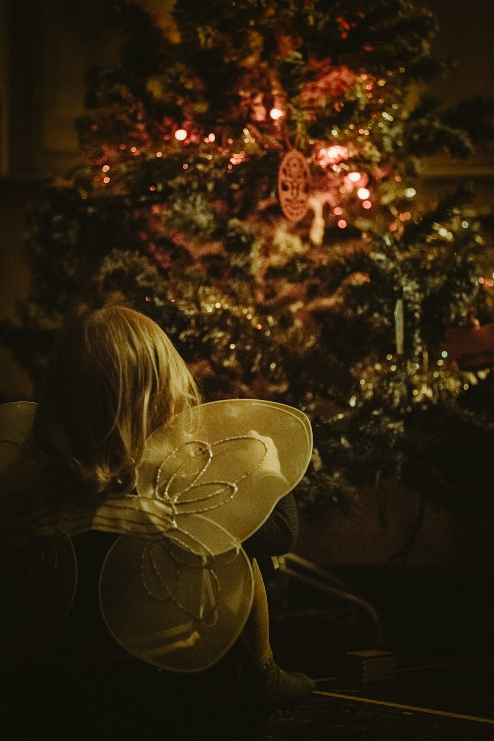 woman in black shirt standing near christmas tree with string lights