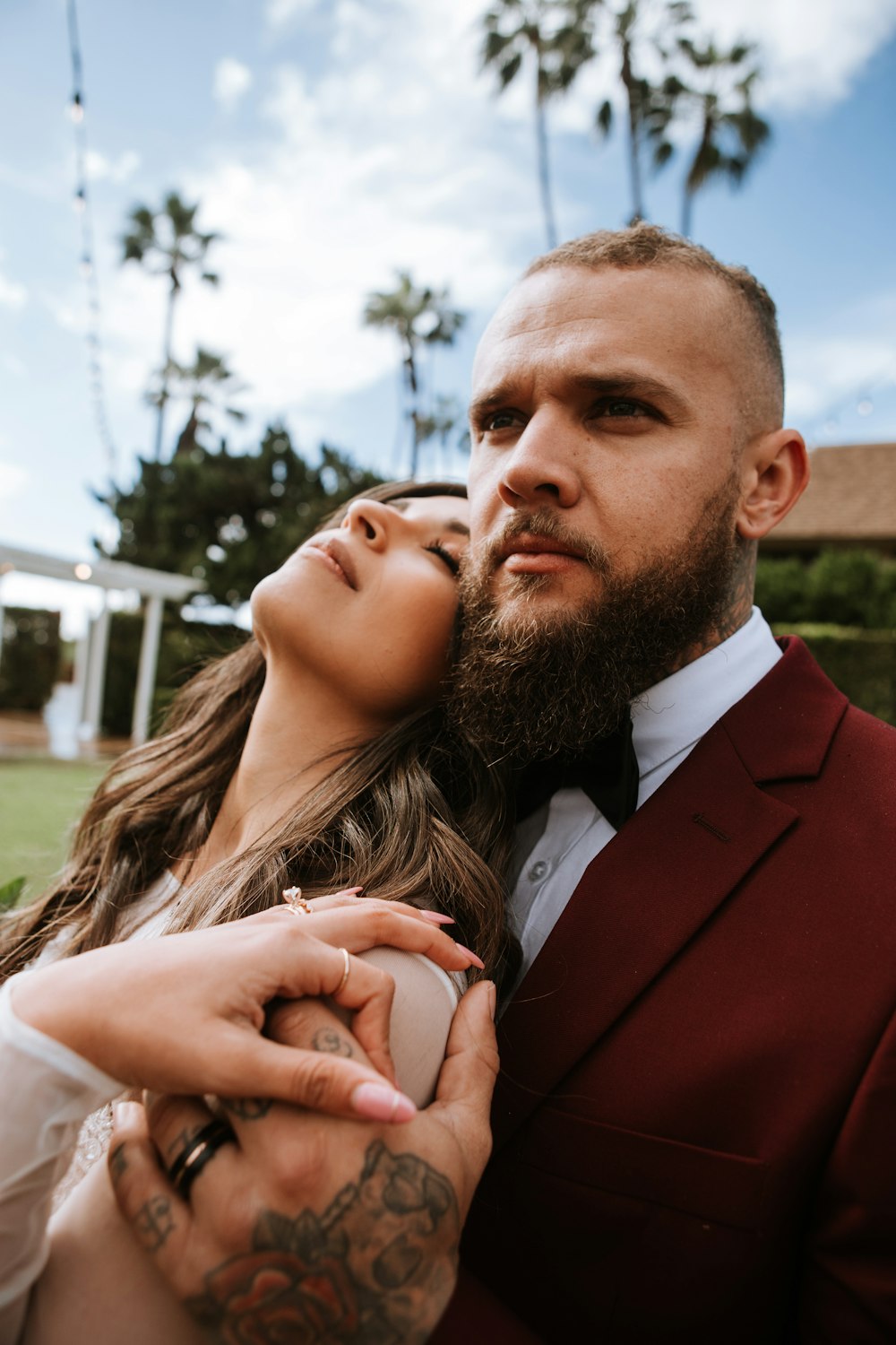 man in red suit jacket kissing woman in white shirt