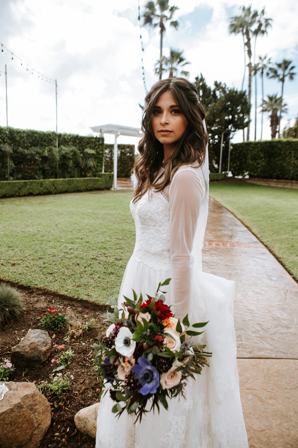 Femme en robe blanche à manches longues tenant bouquet de fleurs