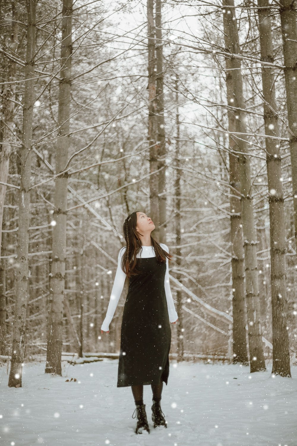 woman in black dress standing in the woods