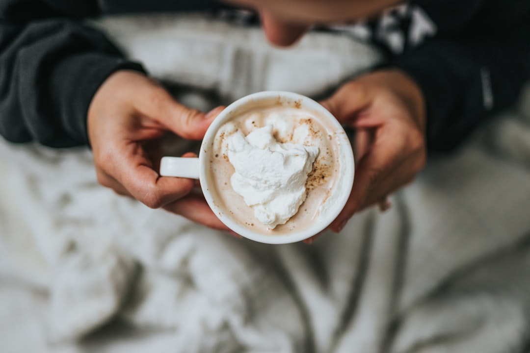 person holding white ceramic mug with white cream