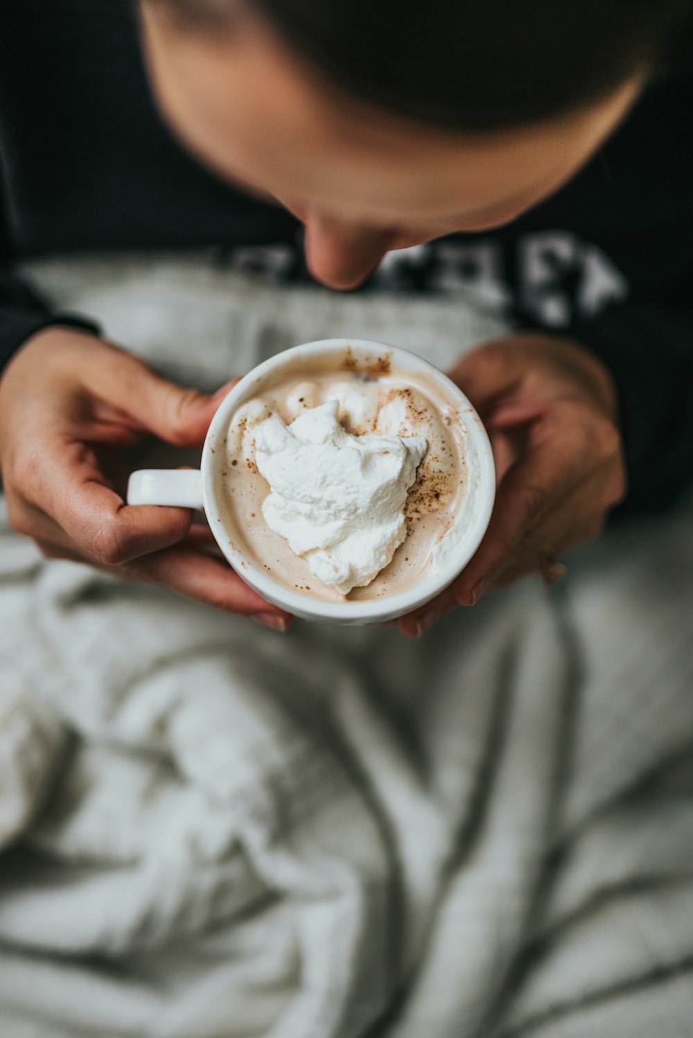 person holding white ceramic mug with brown liquid