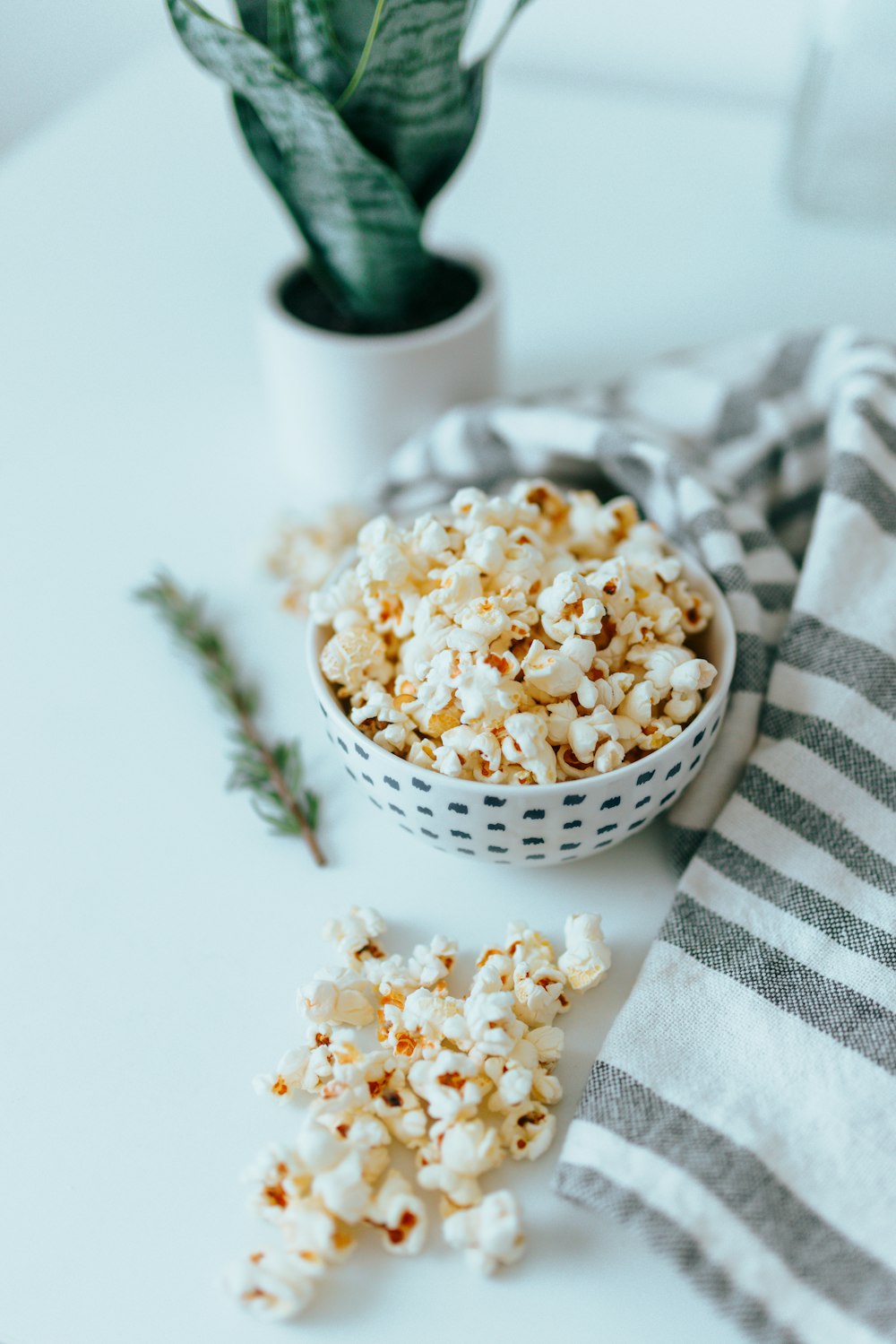 white and black checkered textile beside white ceramic bowl with popcorn
