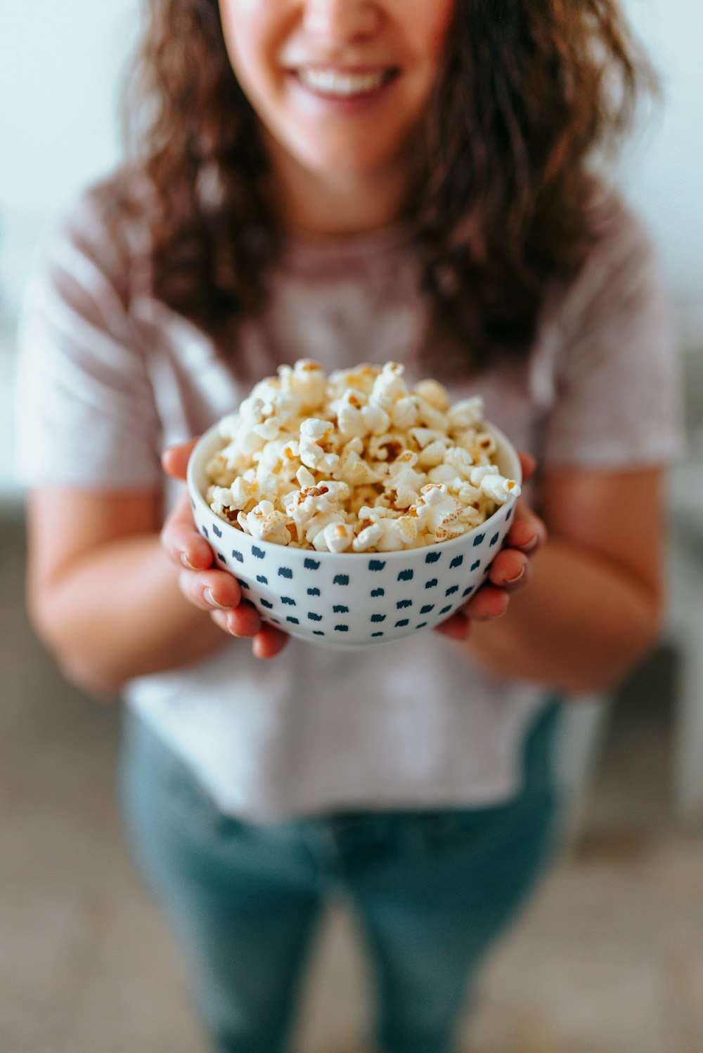 person holding white ceramic bowl with popcorn