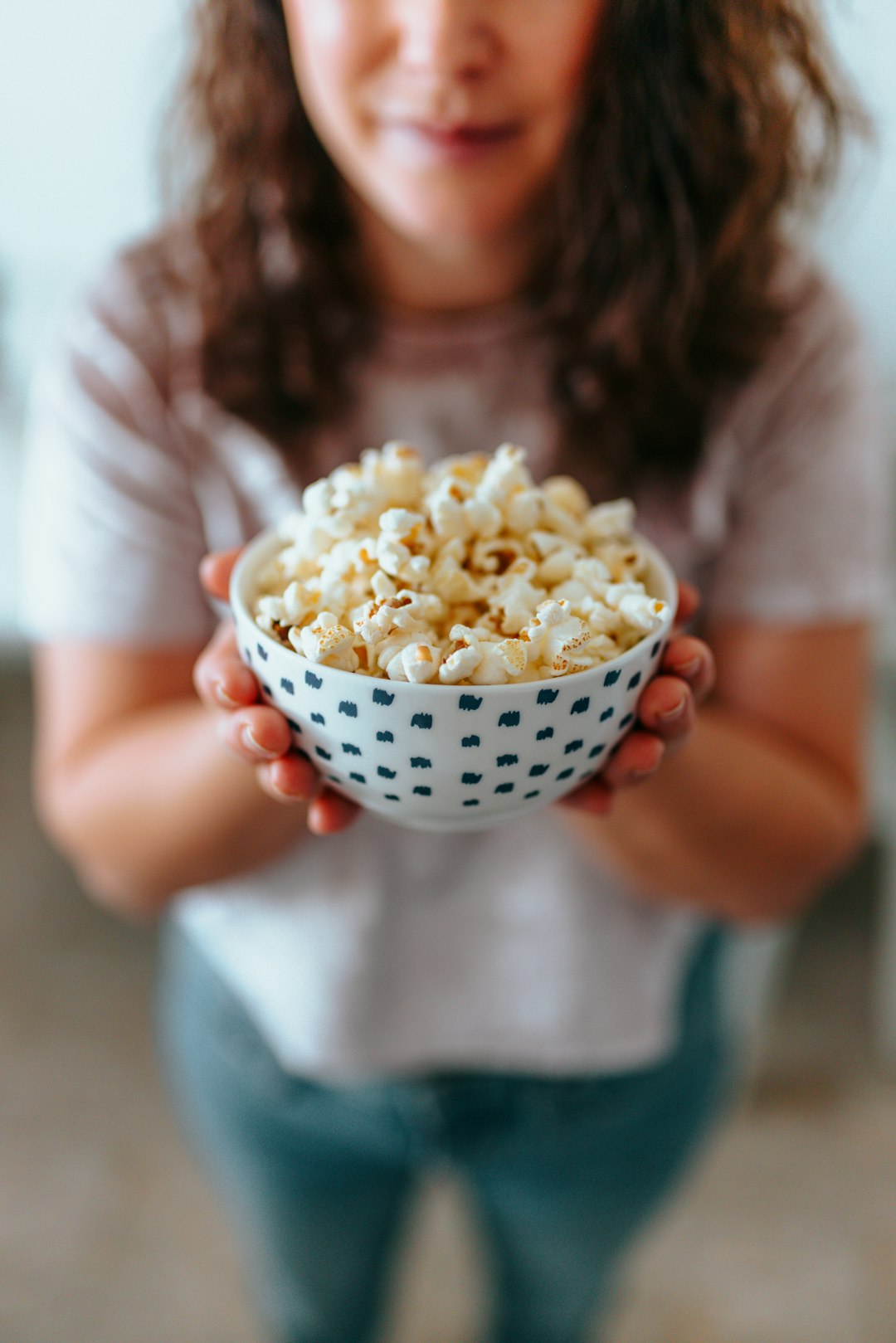 person holding white ceramic bowl with popcorn