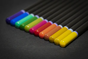 A close-up of colorful pens neatly arranged on a wooden desk
