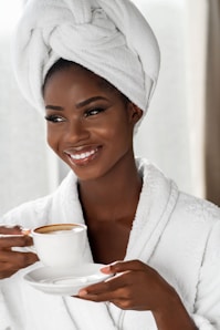 smiling woman in white bathrobe holding white ceramic mug