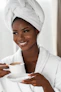 smiling woman in white bathrobe holding white ceramic mug