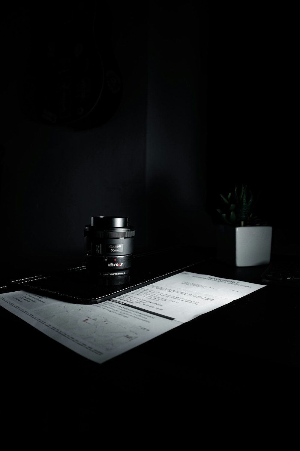 black camera on white printer paper beside green potted plant