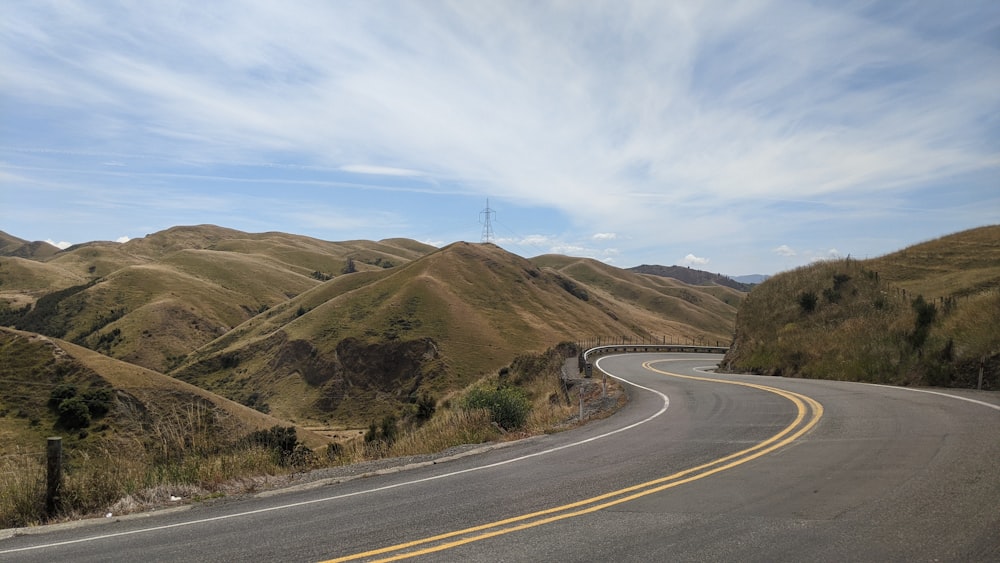 gray concrete road near green mountain under white sky during daytime