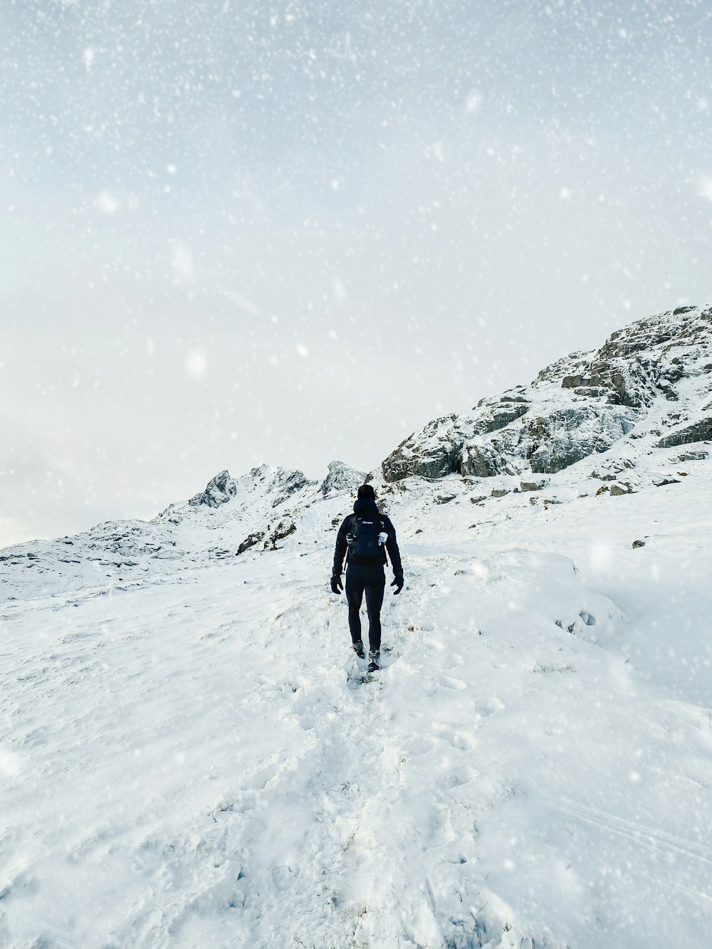 Person in schwarzer Jacke, die tagsüber auf schneebedecktem Boden läuft