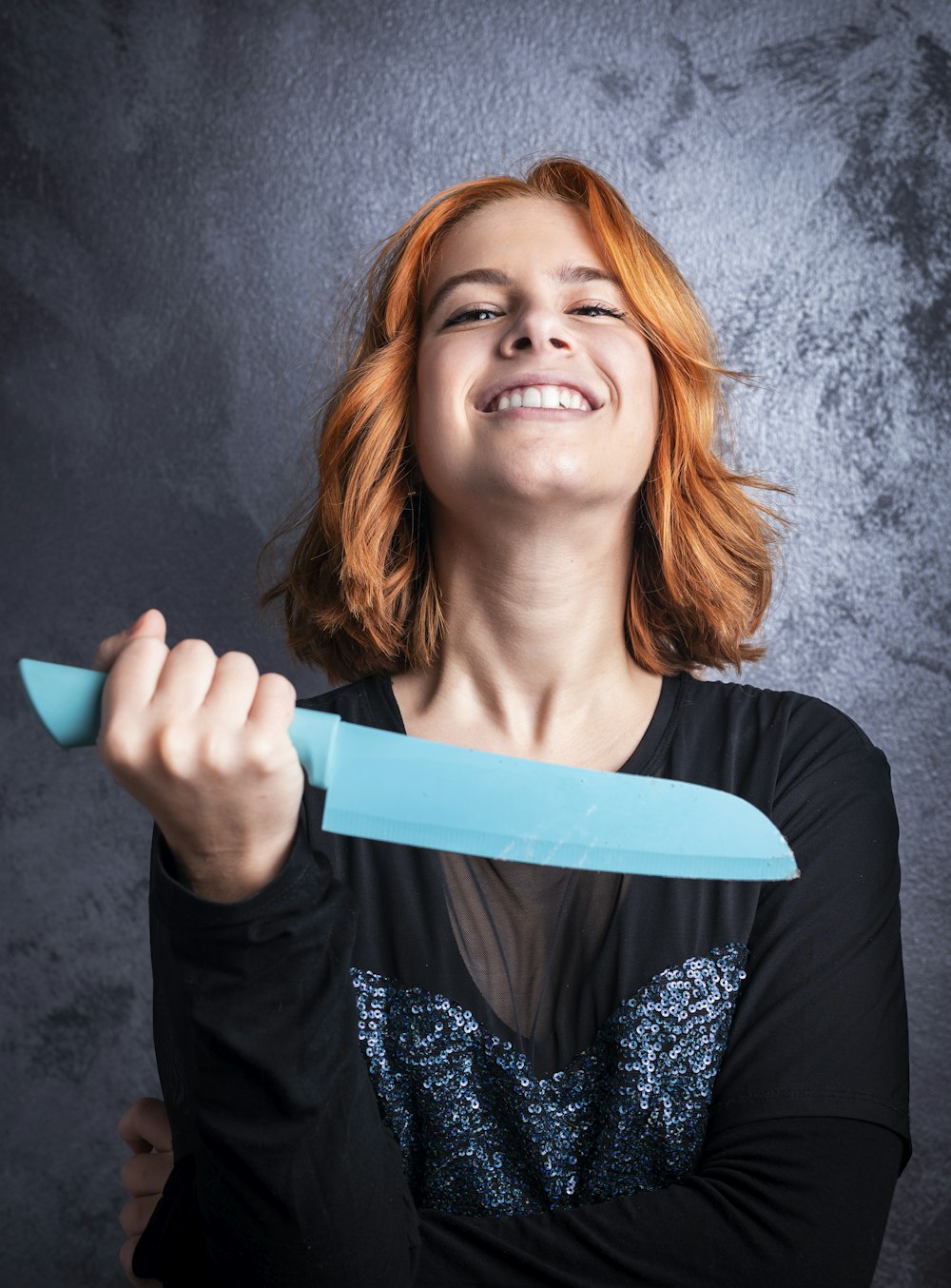 woman in black cardigan holding blue plastic hair comb