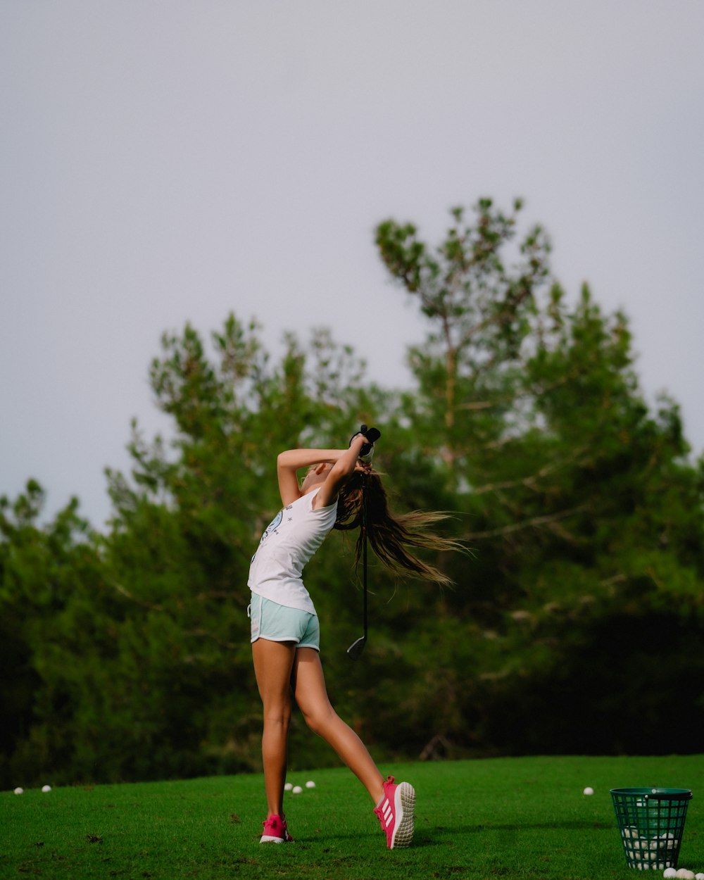 a woman swinging a tennis racquet on top of a green field