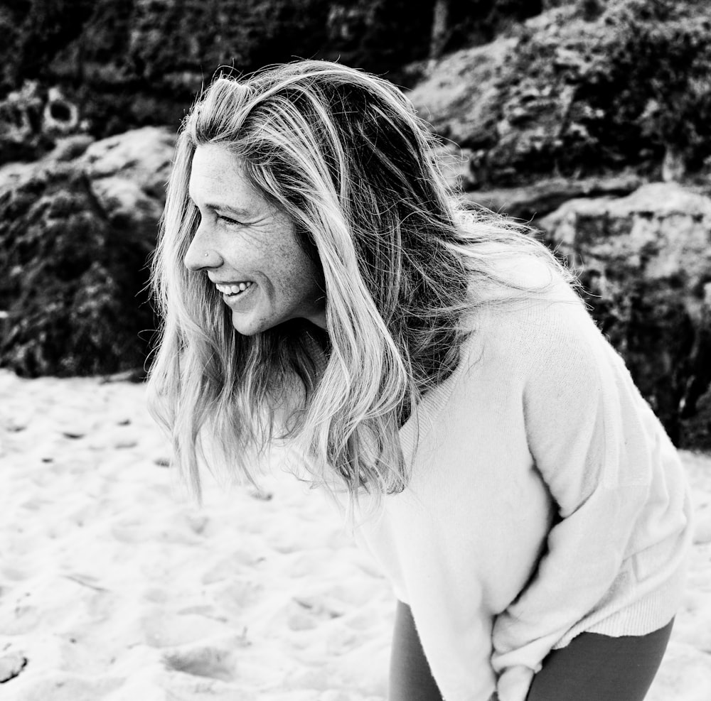 woman in white long sleeve shirt sitting on sand during daytime