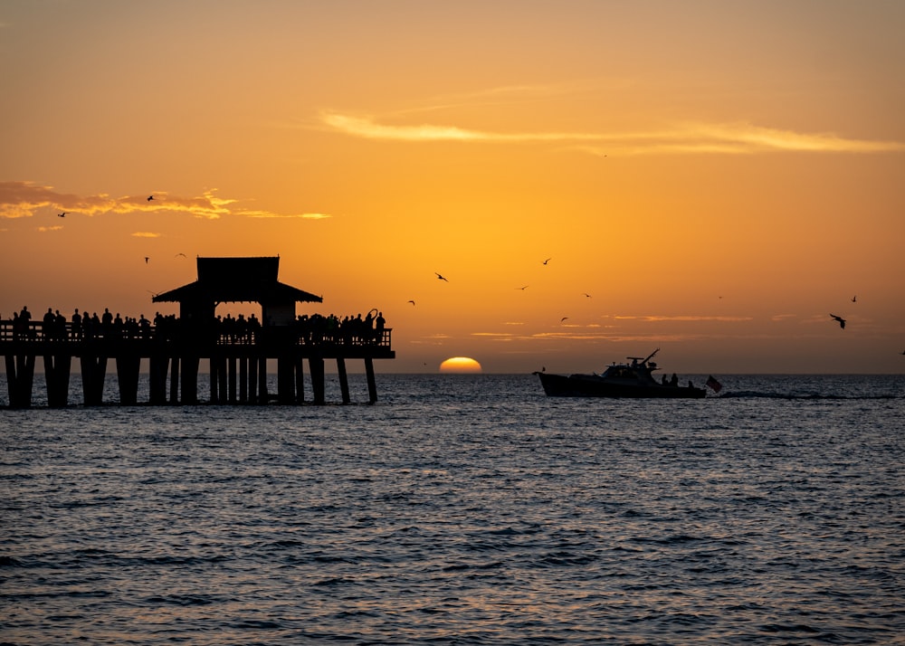 a boat in the water near a pier at sunset