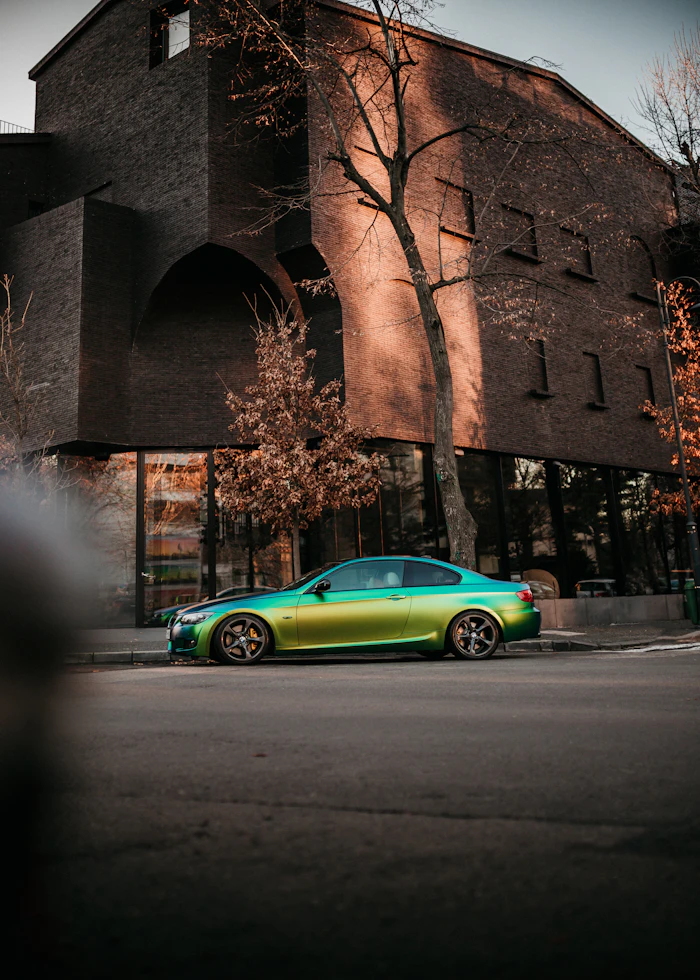Green coupe near brick building