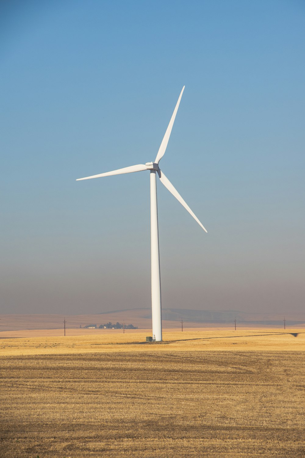 white wind turbine on brown field under blue sky during daytime