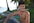 topless man sitting on blue towel near swimming pool during daytime