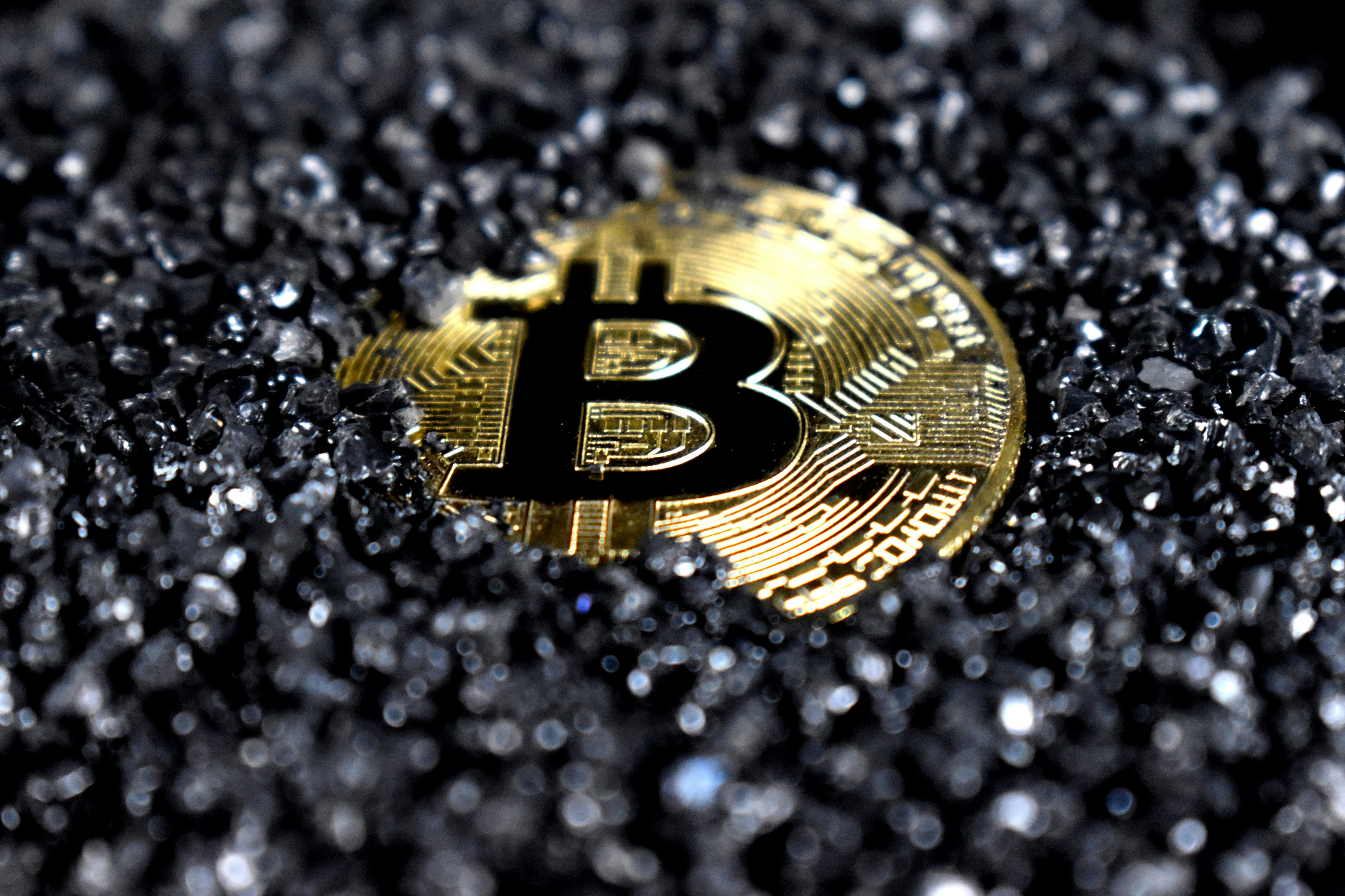 A Bitcoin covered in black crystals.