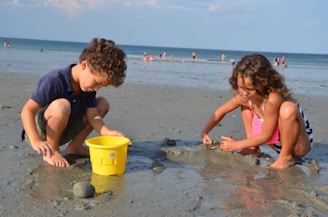 Kids building a sandcastle at the beach with colorful buckets and shovels