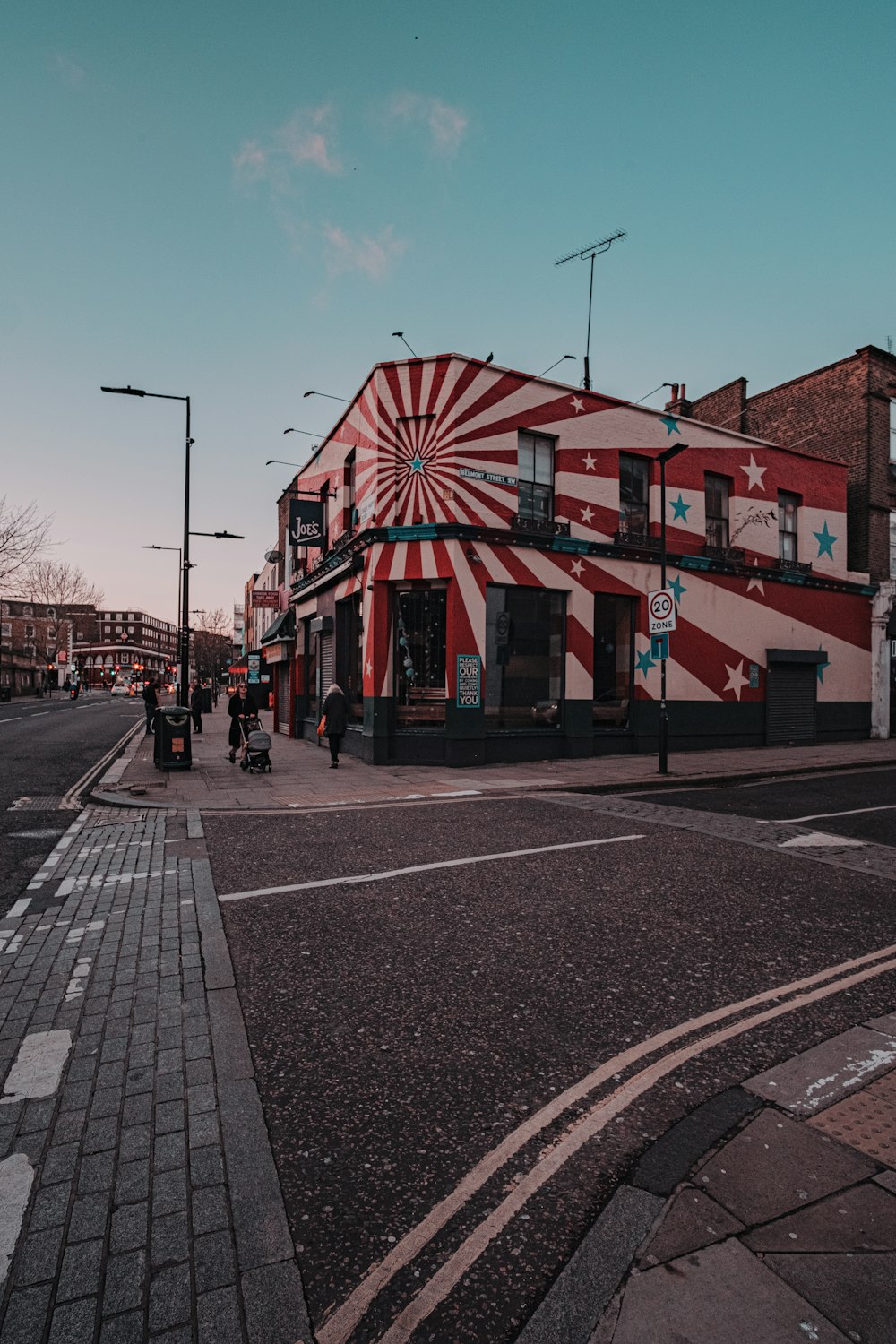 people walking on sidewalk near red and white concrete building during daytime