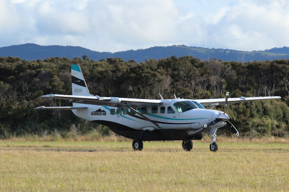 white and blue airplane on green grass field during daytime