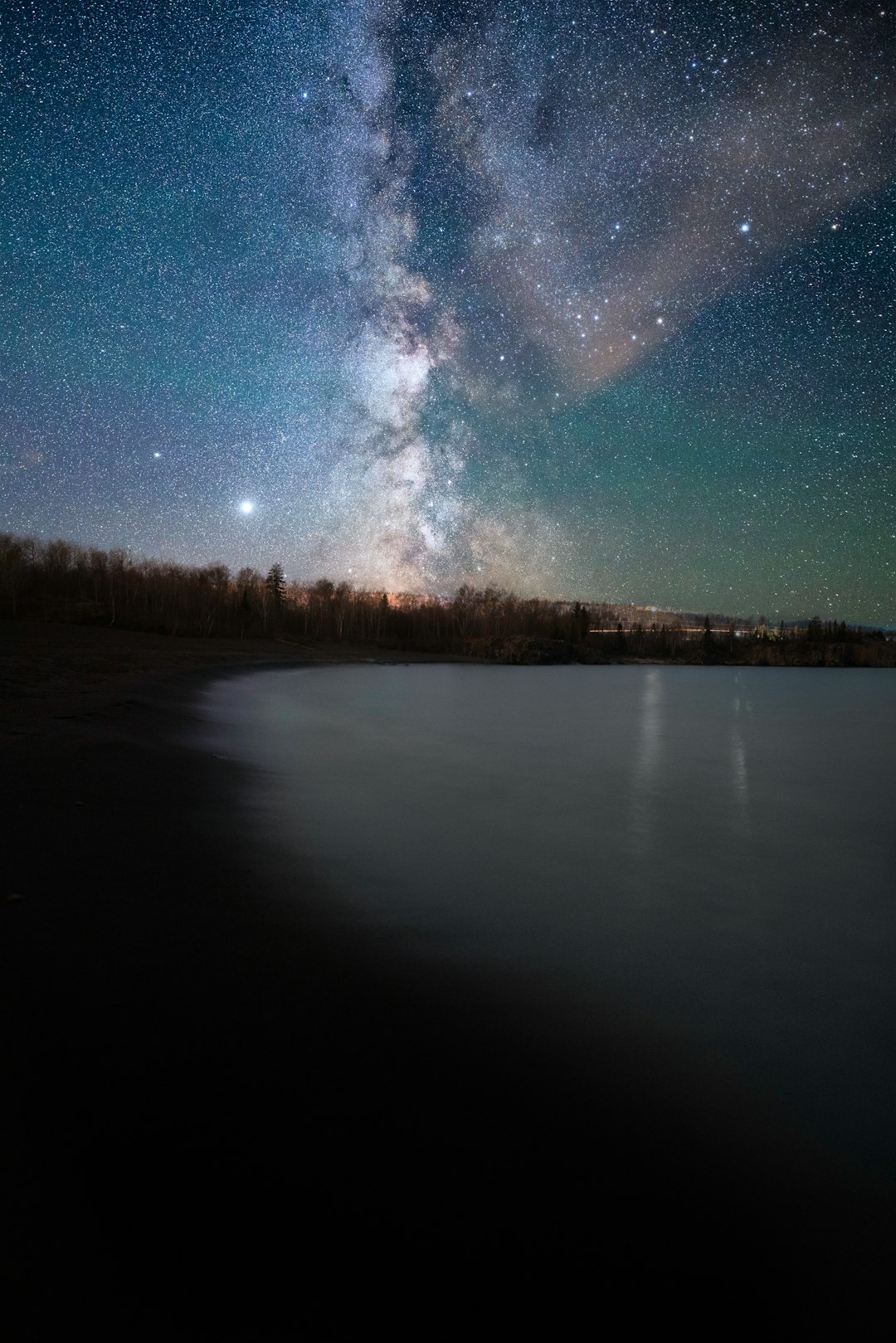 body of water near trees under blue sky during night time