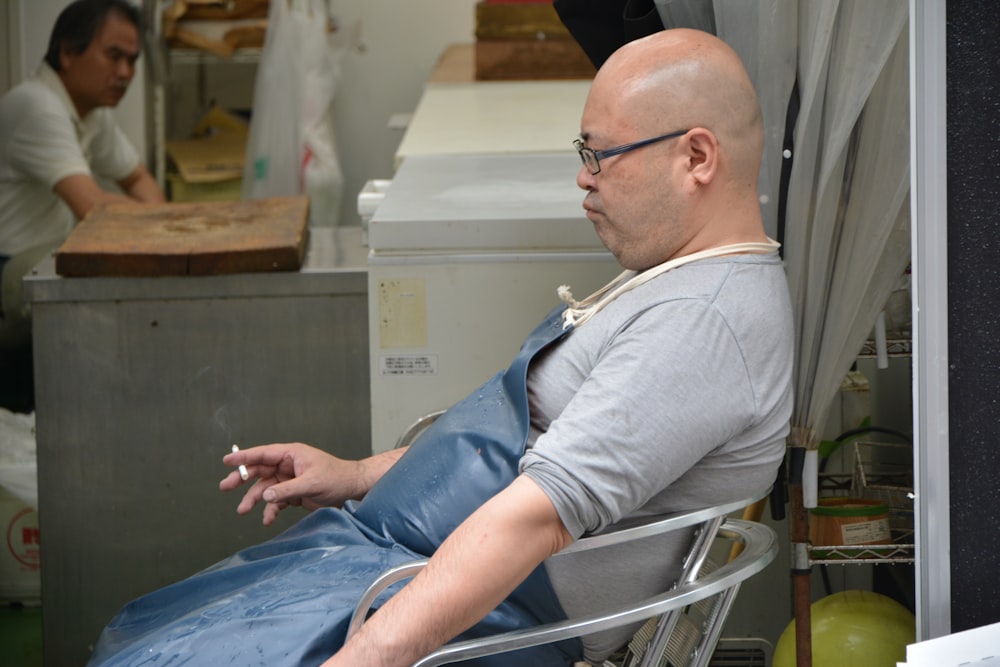 man in white long sleeve shirt and blue denim jeans sitting on chair