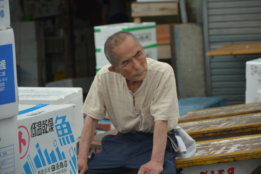 man in white polo shirt and blue pants sitting on brown wooden bench