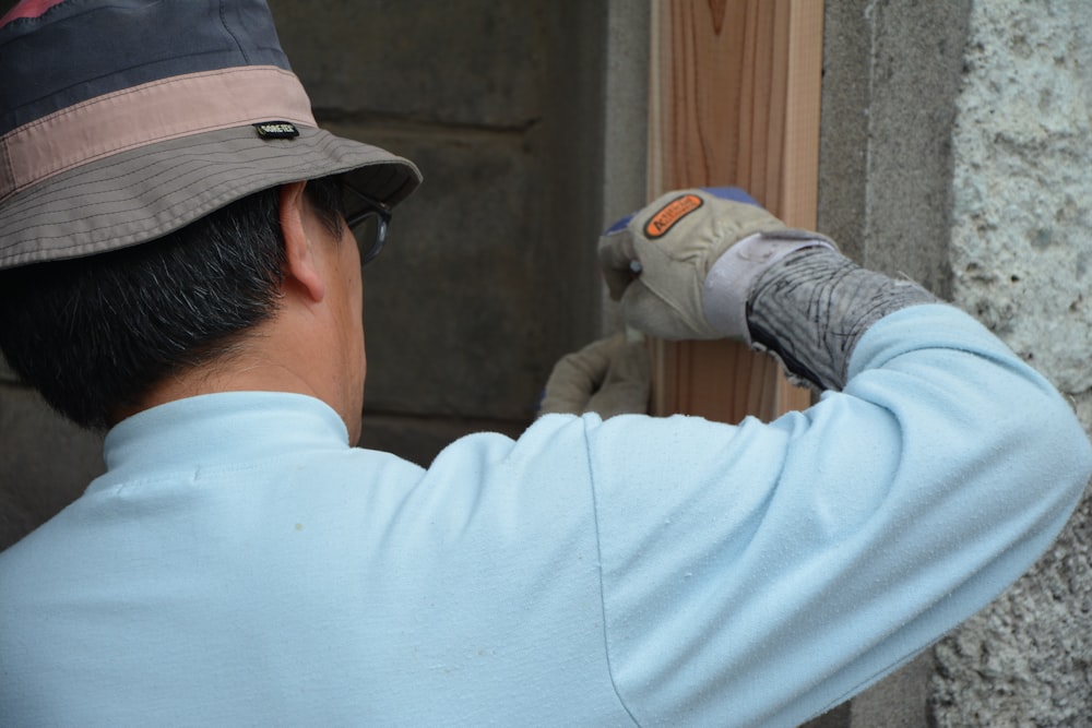 man in white long sleeve shirt and black cap holding gray and white cat