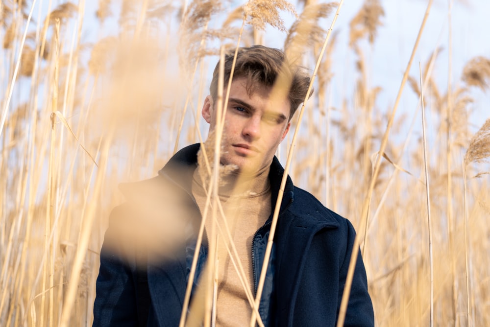 man in black jacket standing on brown grass field during daytime