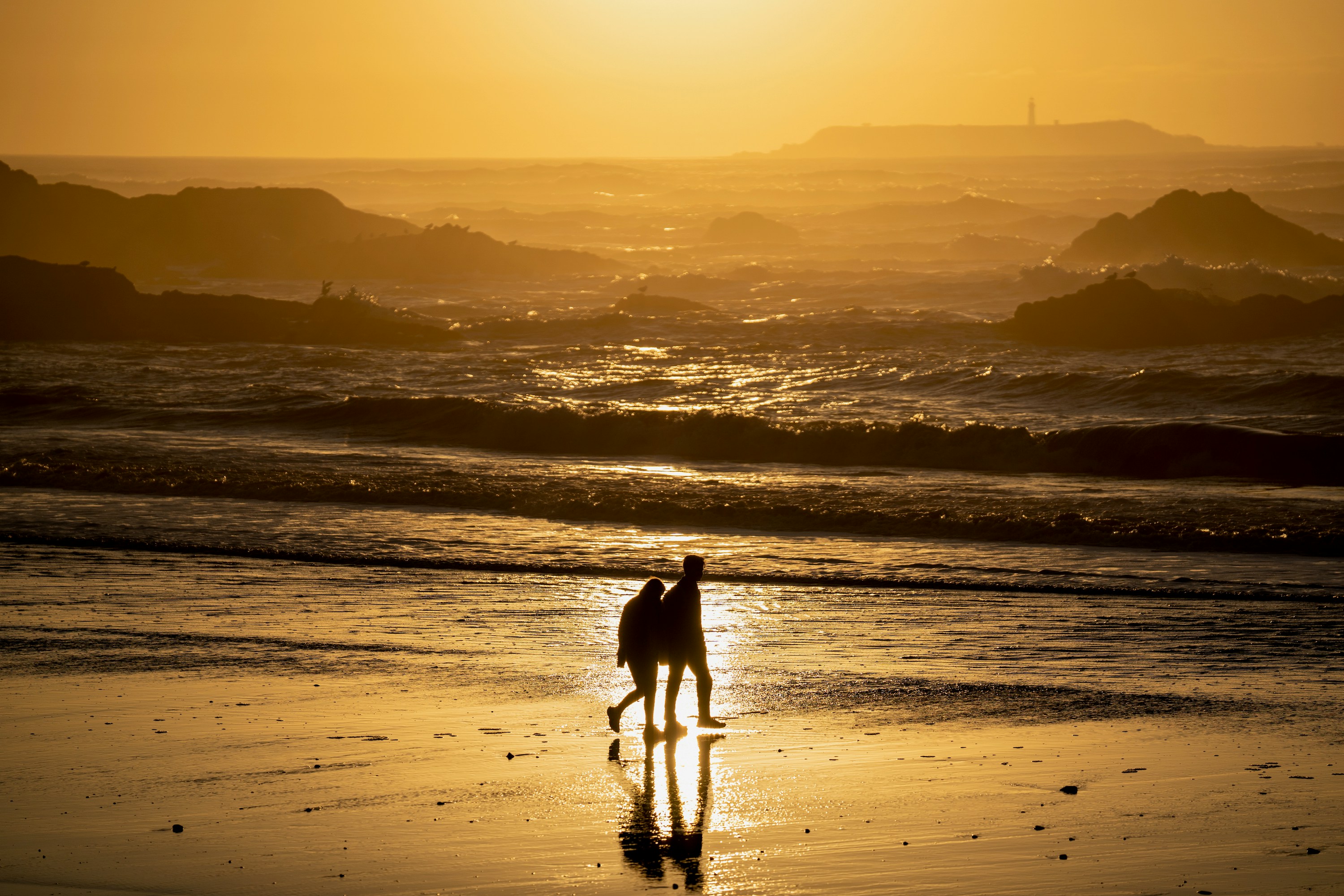 Couple walking on beach at sunset