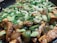 A close-up view of a dish featuring cubed tofu pieces cooked with chopped green onions and bell peppers in a savory sauce.