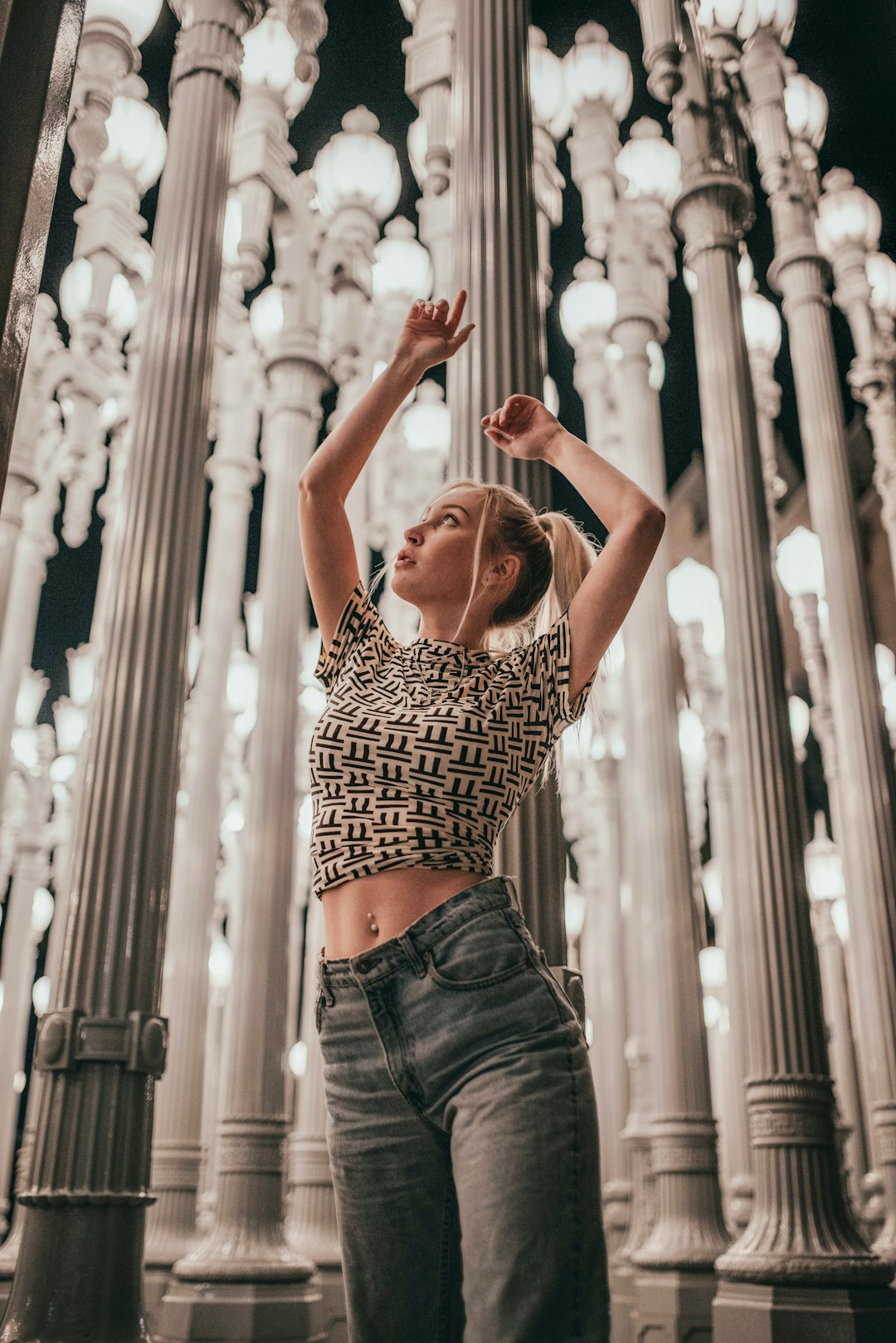 woman in black and white polka dot crop top and blue denim jeans raising her hands