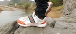 A close-up of trail running shoes on rocky ground.