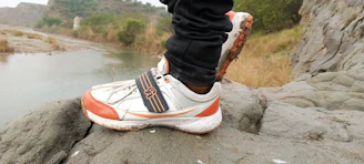 Close-up of trail runner's feet pounding a rugged mountain path surrounded by vibrant natural scenery.