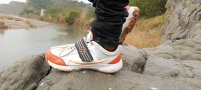 Close-up of trail running shoes on rocky mountain path.