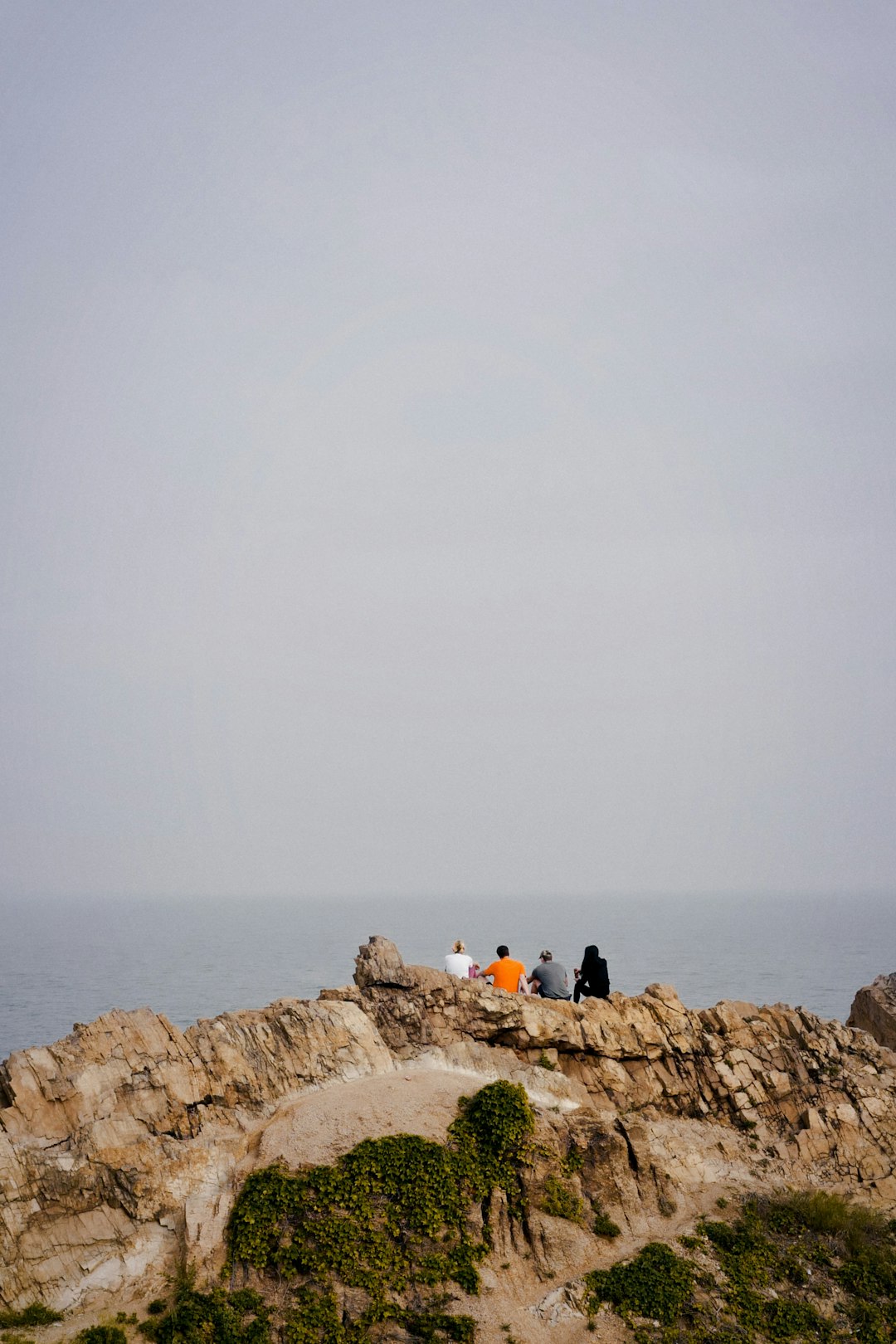 people sitting on brown rock formation near sea during daytime