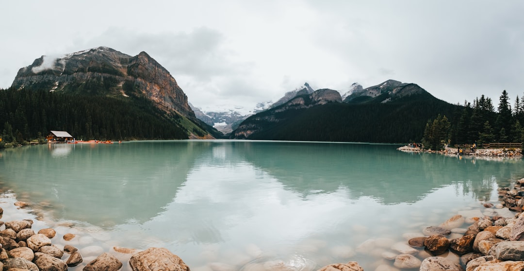 lake near mountain under white sky during daytime